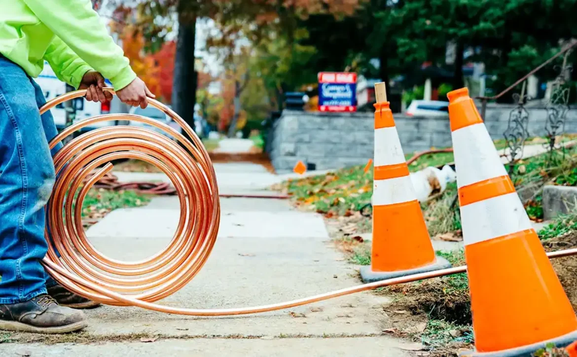 Construction worker rolling out a copper pipe