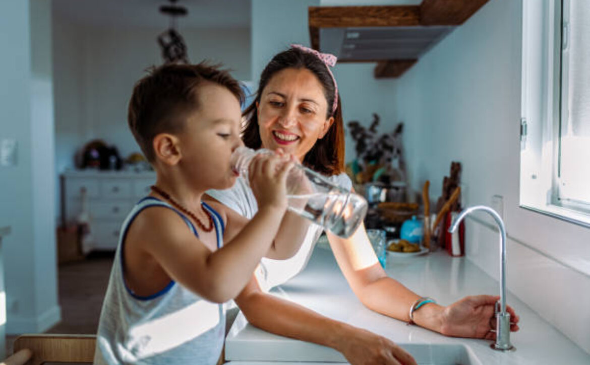 Mother and her toddler filling a glass with filtered water right from the tap