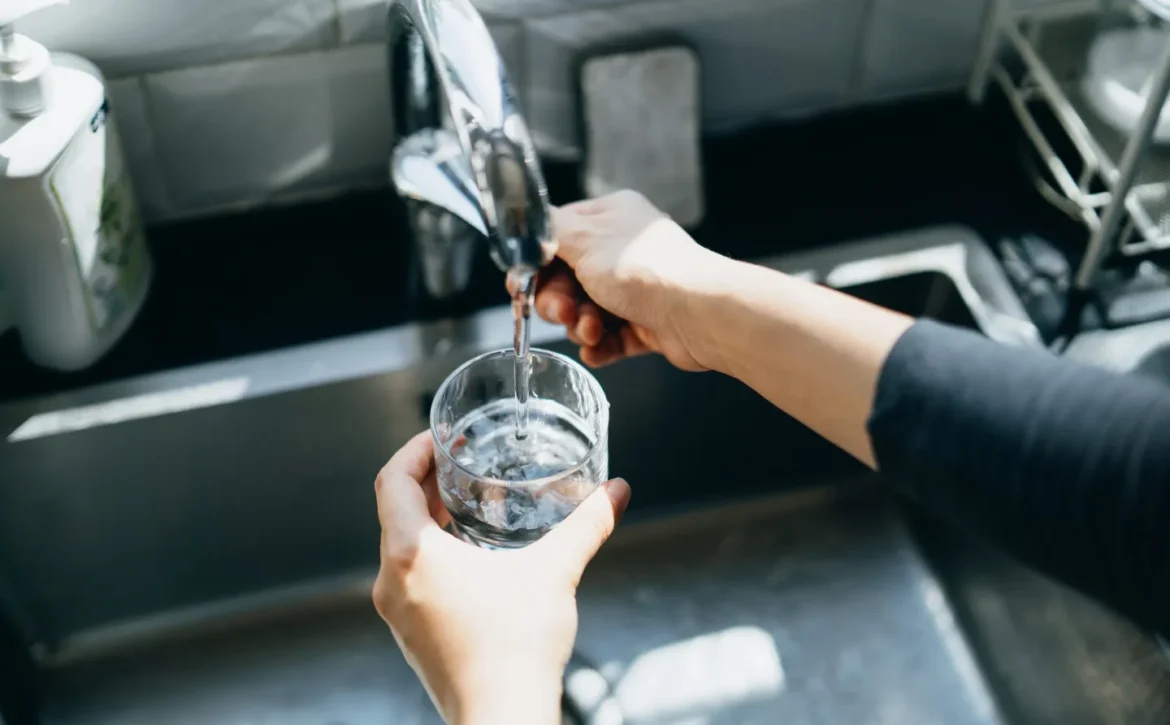 Person at kitchen sink filling a glass of water