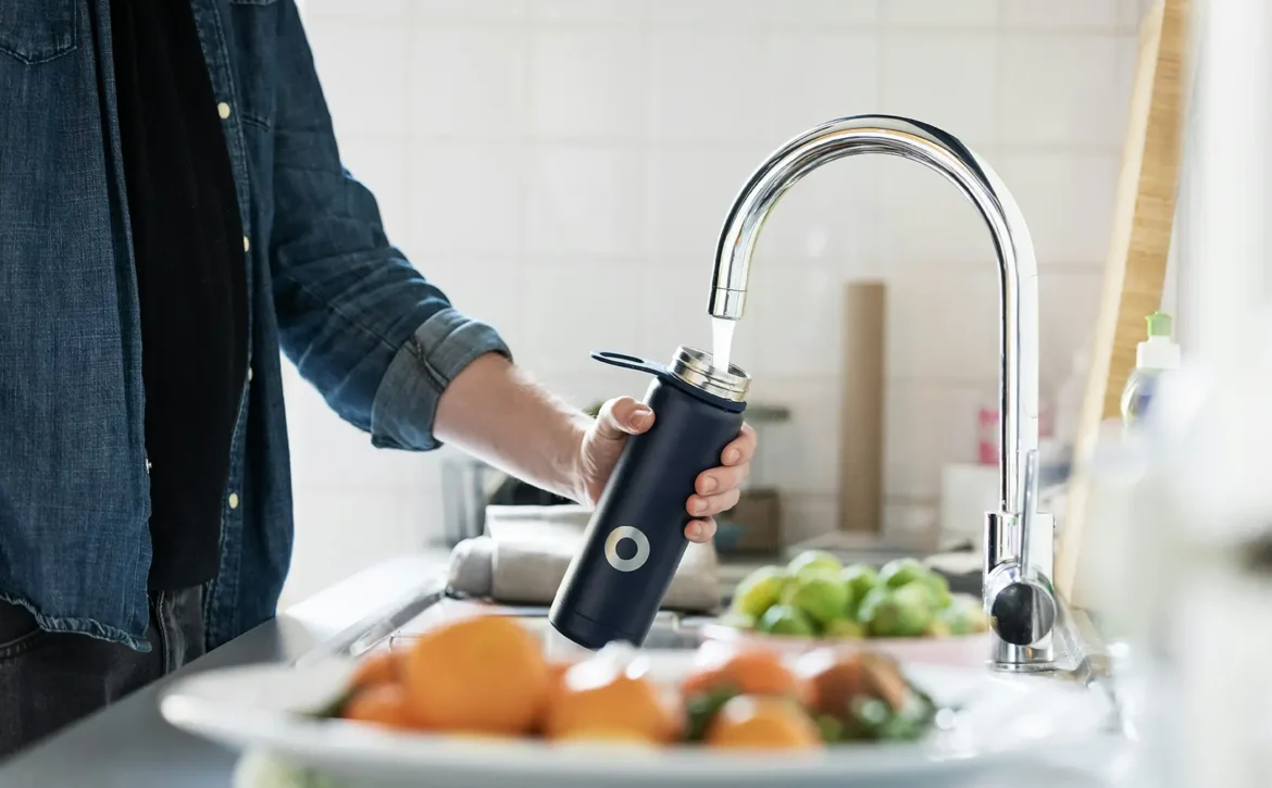 Man filling water bottle at kitchen sink
